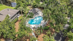 Une propriété résidentielle dotée d’une piscine, entourée d’une végétation luxuriante et comprenant un patio clos.