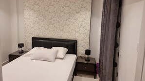A modern bedroom with a bed, a nightstand, an air conditioner, and a curtain. - Rehab City- Appartement Cosy-chic Près de Toutes Commodités (Cairo Governorate)
