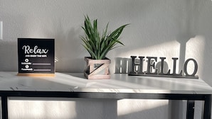 A modern bar area with a 'guests' sign, a 'Relax' sign, a 'HELLO' sign, and two stools. - Harrisburg apt Great River View (Harrisburg)