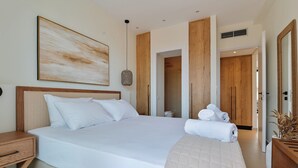 A modern hotel room with a large bed, wooden wardrobe, and a large painting on the wall. - Melior Villas (Preveza)