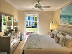 Un dormitorio con cama, lámparas de noche, cómoda y ventilador de techo.