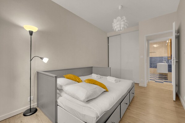 A bedroom with a bed, bedside lamp, and a view into the bathroom. - Roma Maximus - en plein coeur historique vieille ville (Toulouse)