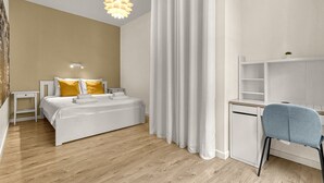 Un dormitorio moderno con cama, mesita de noche y escritorio con silla.