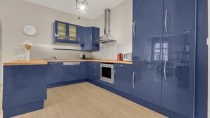 Una cocina moderna con armarios azules, una campana extractora de acero inoxidable y una encimera de madera.