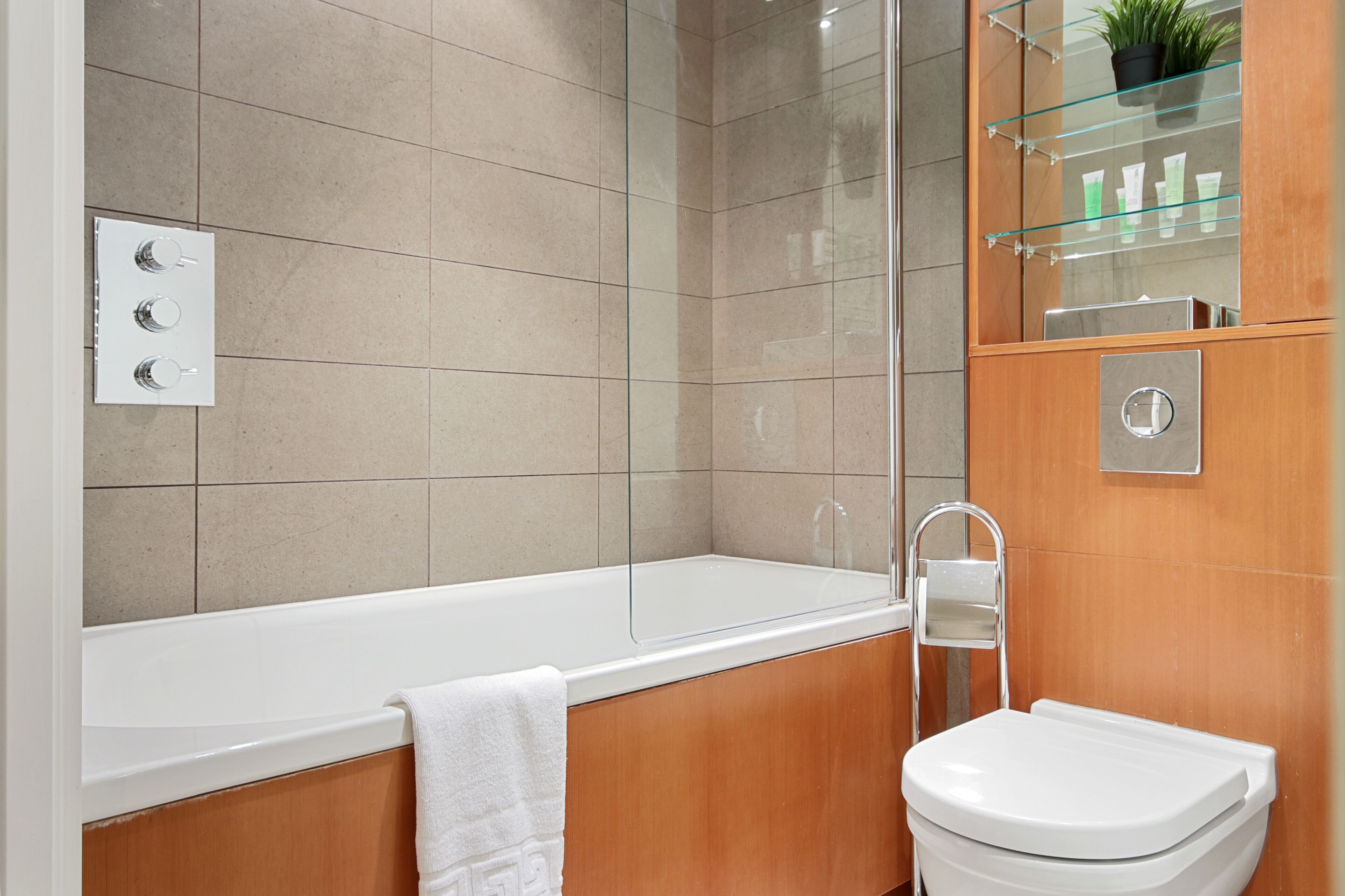 A bathroom with a bathtub, a toilet, and a glass shower enclosure.