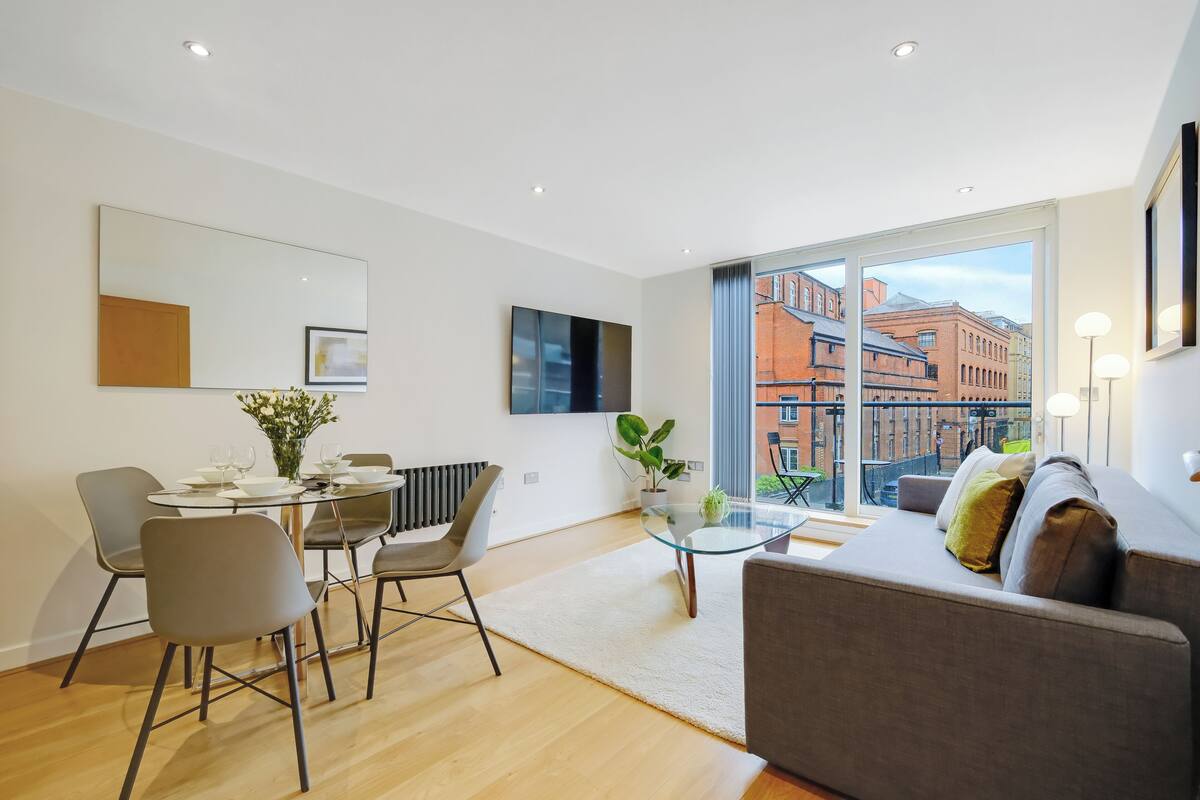 A modern living room with a dining area, large windows, and a view of buildings.