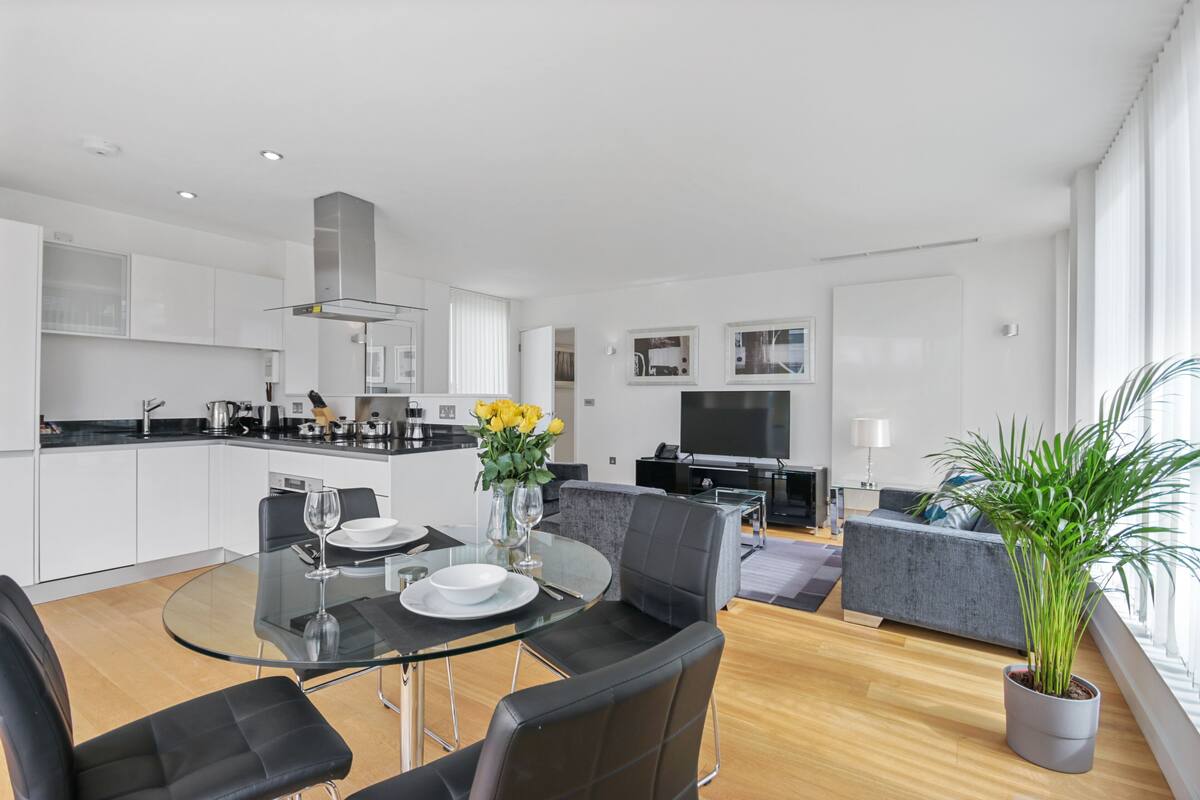 A modern apartment with a dining area, kitchen, living room, and a large window.