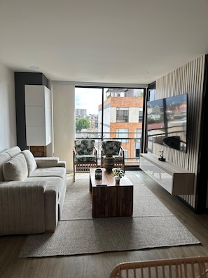 A modern living room with a sofa, chairs, a coffee table, and a TV.