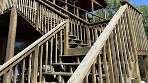 A wooden staircase leading to a covered porch with a metal railing.