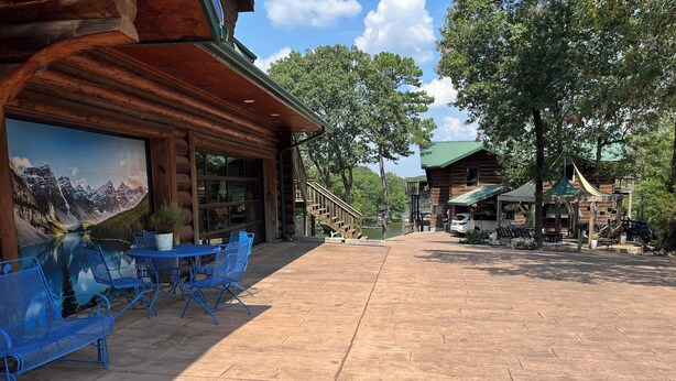 A wooden lodge with outdoor seating and a mountain view mural.