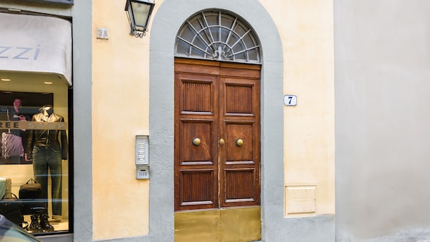 A double wooden door with a brass lower section, a small window above, and a number '7' on the wall. - Il Nido di Santa Croce by Mmega (Florence)