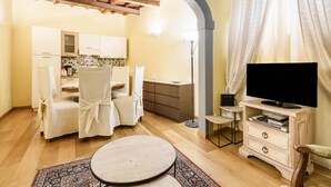 A cozy living room with a dining area, a television, and a kitchen in the background. - Il Nido di Santa Croce by Mmega (Florence)