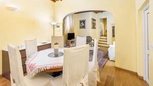 A dining area with a round table, white chairs, and a wooden ceiling. - Il Nido di Santa Croce by Mmega (Florence)