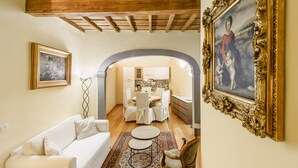 A living room with a white sofa, a patterned rug, and a dining area with a table and chairs. - Il Nido di Santa Croce by Mmega (Florence)