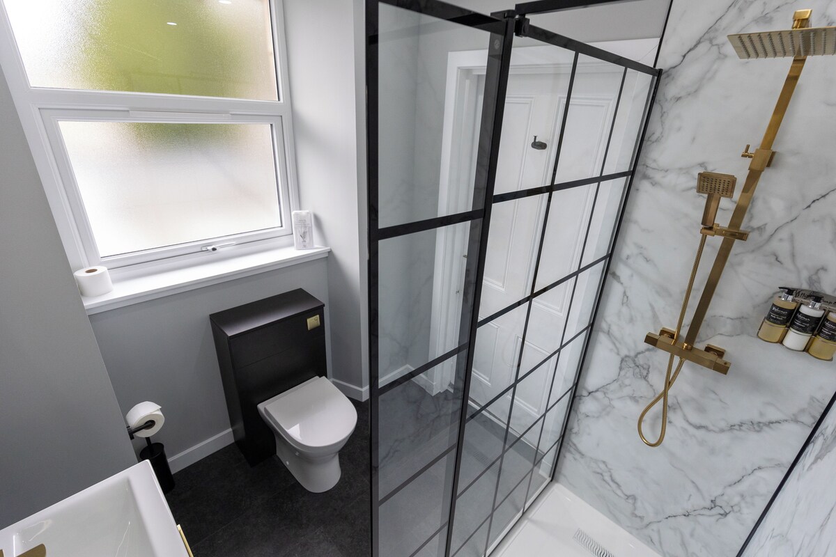 Un baño moderno con cabina de ducha de vidrio, inodoro y ventana.