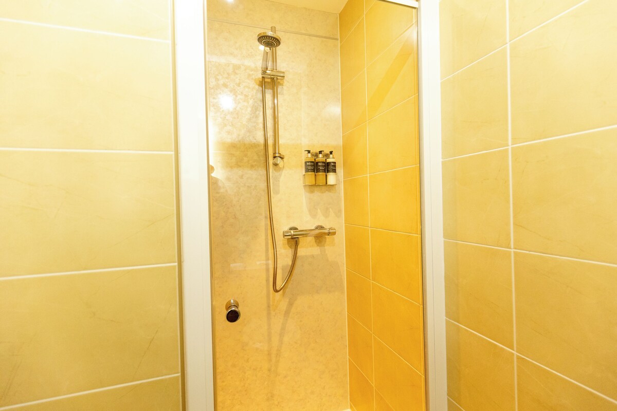 Un baño con azulejos amarillos, ducha e inodoro.
