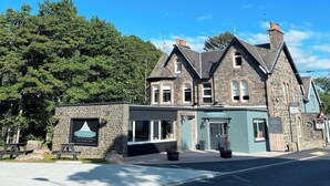 A stone building with a sign reading "The Crossing" and a small outdoor seating area. - The Crossing (Kingussie)