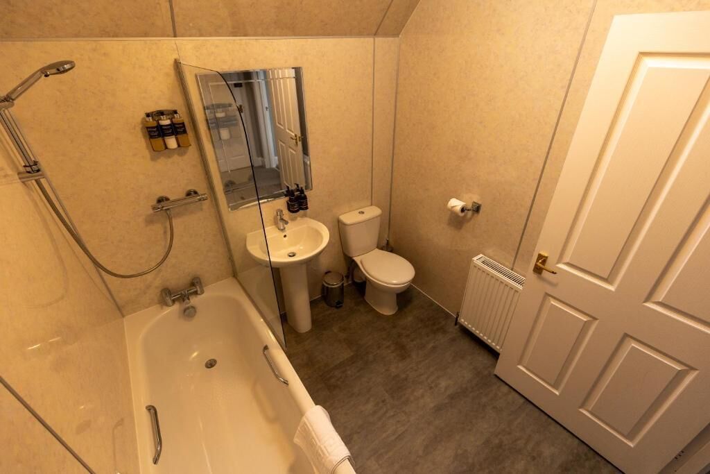 A bathroom with a bathtub, sink, toilet, and a mirror.