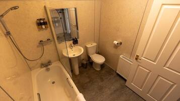 A bathroom with a bathtub, sink, toilet, and a mirror.
