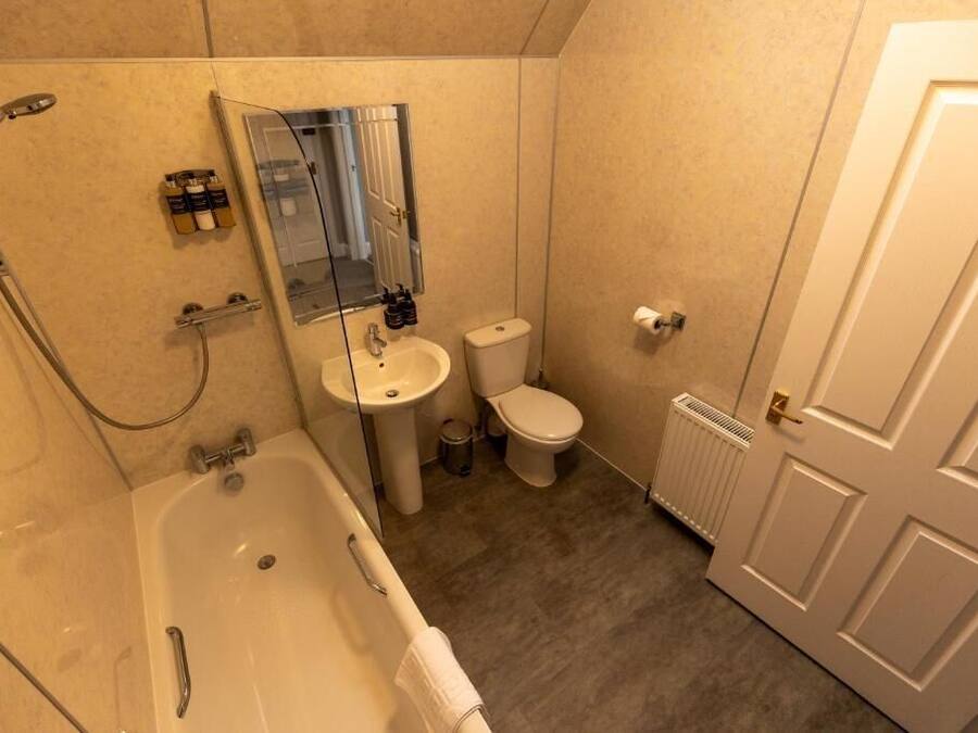 A bathroom with a bathtub, sink, toilet, and a mirror.