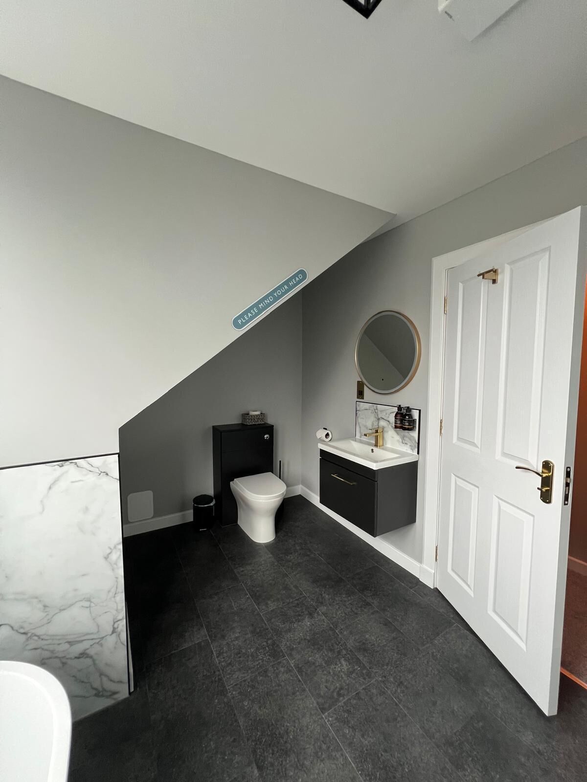 Ein modernes Badezimmer mit Toilette, Waschbecken und Spiegel.