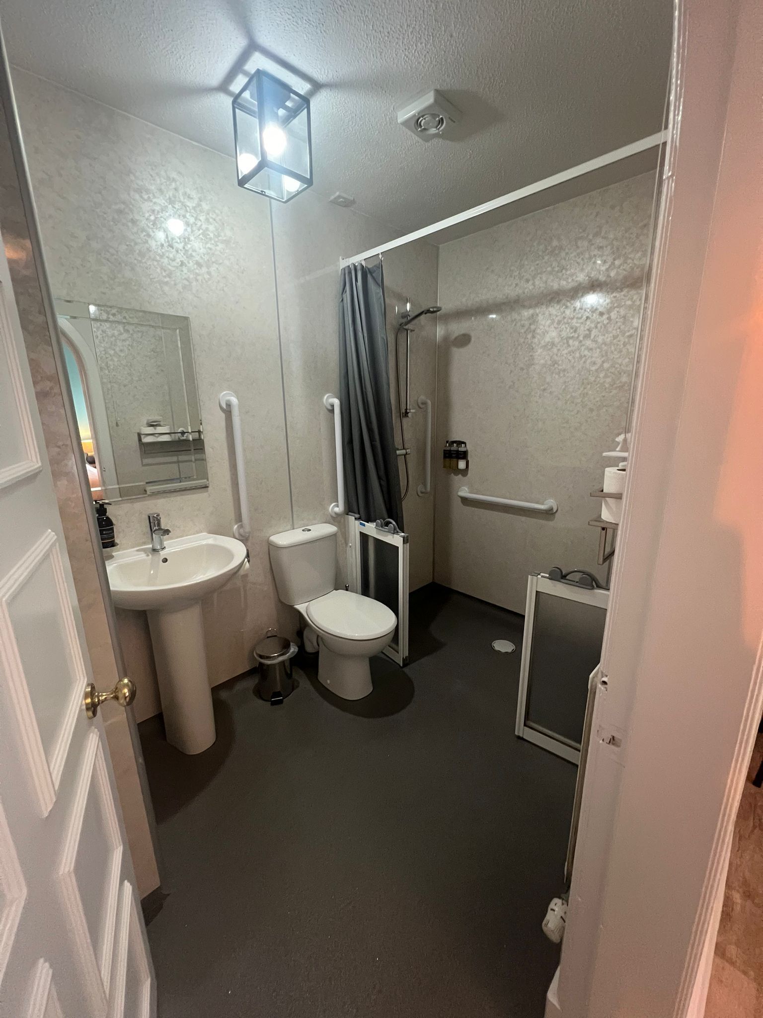 Un baño pequeño con lavamanos pedestal, inodoro y ducha.