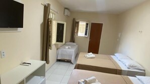 Camera d'albergo con due letti singoli, una scrivania con sedia, una televisione a parete e una finestra con tende.