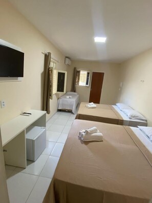 A hotel room with two single beds, a desk with a chair, a television mounted on the wall, and a window with curtains. - Pousada Manaíra (João Pessoa)