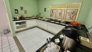Una cucina con una parete verde, un piano di lavoro nero e diversi alimenti ed elettrodomestici.