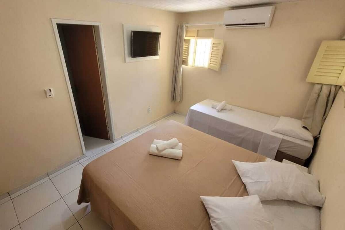 A hotel room with a bed, a bedside table, a TV, and a window with curtains.