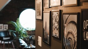 Un mur orné de tableaux encadrés et une grande fenêtre circulaire.