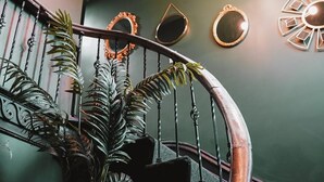 Un escalier en colimaçon avec une rampe en bois, une plante en pot et un miroir fixé au mur.