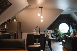Un loft moderno con cocina, comedor y sala de estar. Cuenta con una isla de cocina, una mesa de comedor y un sofá de cuero negro.