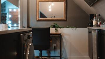 A compact kitchen with a washing machine, a desk, and a mirror.