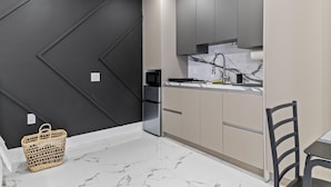 A modern kitchen with dark walls, a stainless steel refrigerator, and a marble countertop. - XL Luxury Room. Luxurious studio retreat with sleek designs. (Miami)