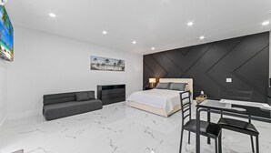A modern hotel room with a bed, a sofa, a desk, and a chair. - XL Luxury Room. Luxurious studio retreat with sleek designs. (Miami)