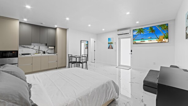 A modern bedroom with a large bed, a desk, and a TV. - XL Luxury Room. Luxurious studio retreat with sleek designs. (Miami)
