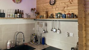 Une cuisine avec des murs en bois, un évier et divers ustensiles de cuisine accrochés au mur.
