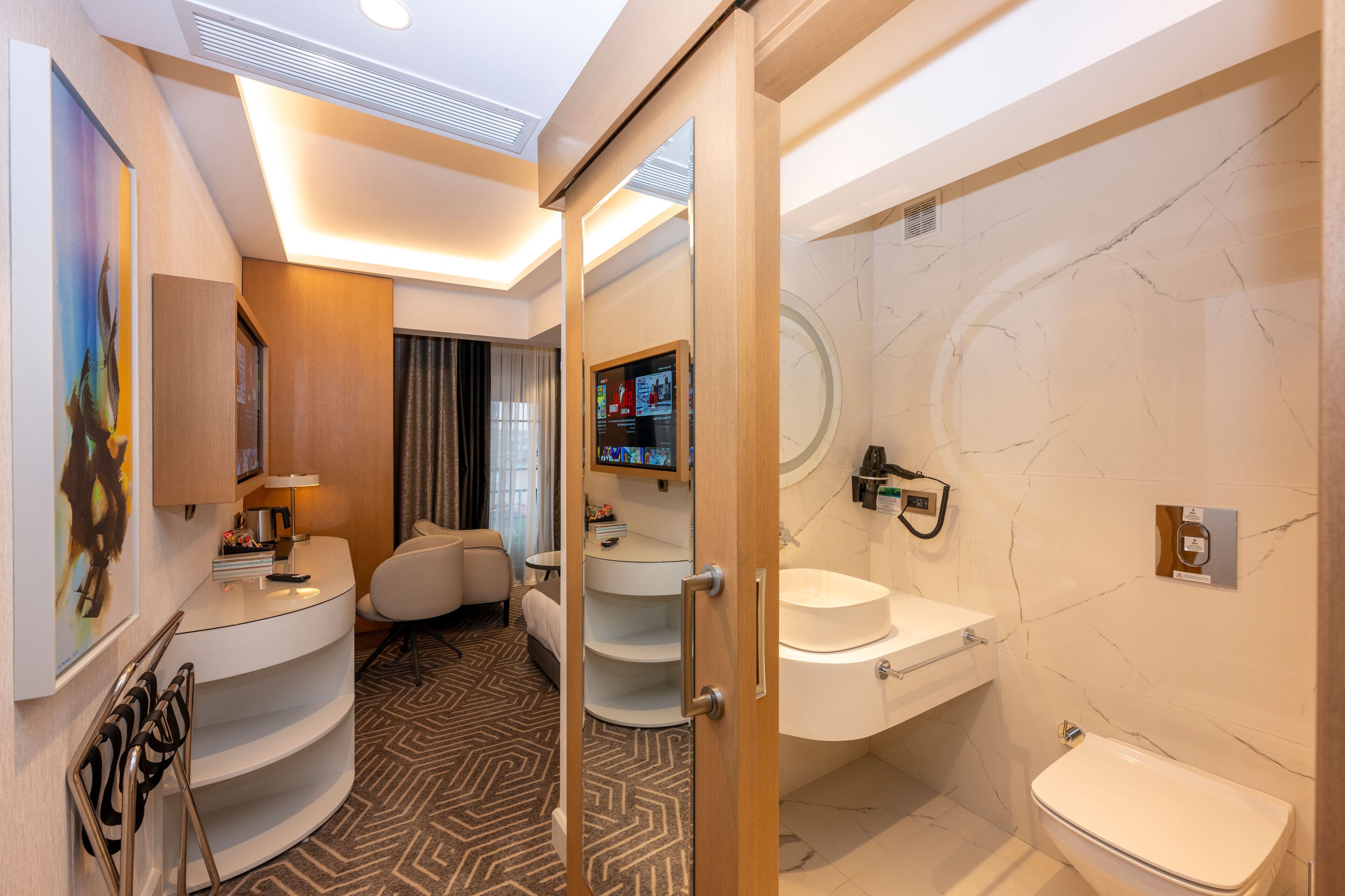 Ein modernes Hotelbad mit Waschtisch, Toilette und Duschbereich.