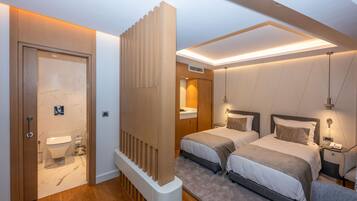 Une chambre d’hôtel moderne avec une porte en bois, une salle de bain, deux lits, une table de chevet et un luminaire au plafond.
