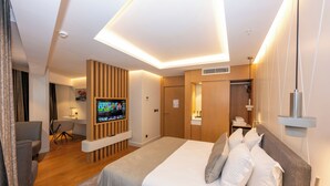Una habitación de hotel moderna con una cama grande, un televisor montado en la pared, un escritorio y un armario.