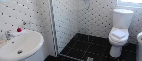 A bathroom with a white sink, toilet, and shower. The walls have a geometric tile pattern.