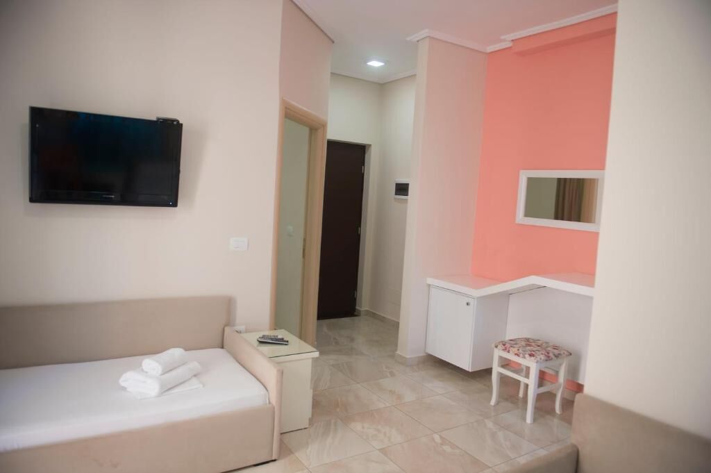 Une chambre d’hôtel avec un lit, une petite table, un téléviseur fixé au mur et un bureau avec une chaise.