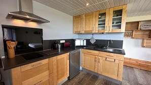 Een kleine keuken met houten kastjes, een rvs afzuigkap, een broodrooster en een vaatwasser.