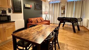 A cozy interior with a wooden dining table, chairs, a sofa, and a ping pong table. - Gîte "La Cordonnerie (MONTGAILLARD LAURAGAIS)