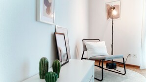 A modern room with a white console table, a black metal bench, a floor lamp, and two framed pictures on the wall. - Pink Flat  (Chiasso)