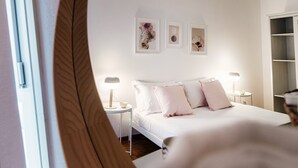 A bedroom with a bed, bedside tables, and wall-mounted artwork. - Pink Flat  (Chiasso)