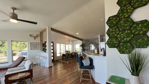 A spacious living area with a wooden floor, a dining table, and a bar area. - Stylish Lake Retreat on Blue Bay, Flathead Lake, Montana with private beach! (Polson)