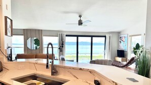 A modern kitchen with a marble countertop, a built-in sink, and a view of the sea through large windows. - Stylish Lake Retreat on Blue Bay, Flathead Lake, Montana with private beach! (Polson)