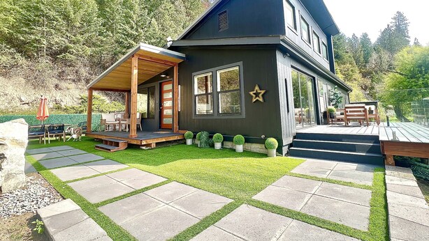 A modern two-story house with a covered porch, a stone pathway, and a well-maintained lawn. - Stylish Lake Retreat on Blue Bay, Flathead Lake, Montana with private beach! (Polson)